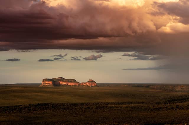 Twin sandstone mesa formations glowing amber under a dramatic storm sky across the flat Cerrado savanna on a Jalapão tour in Brazil