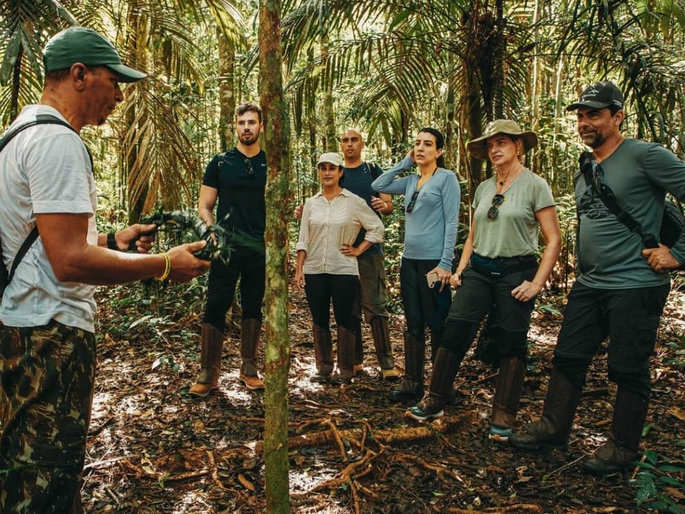 Local guide explaining the flora to a group of tourists during a jungle hiking tour in the Amazon Rainforest.