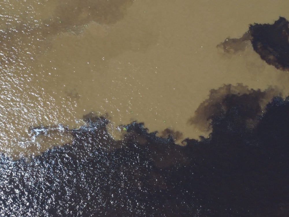 The dark waters of the Rio Negro and the sandy waters of the Rio Solimões flow side by side without mixing during an Amazon boat tour.