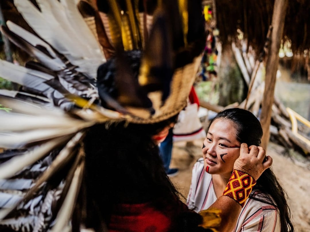 Traveler receiving traditional Indigenous face paint during a community visit in the Amazon