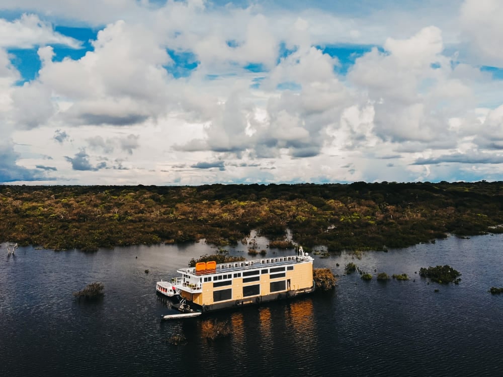 Aerial view of the Untamed luxury riverboat moored on the Rio Negro, surrounded by the flooded Amazon rainforest.