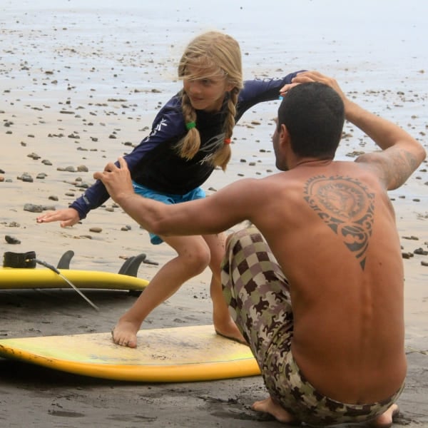 A child taking a surf lesson on the beach at Itacaré, Bahia, Brazil.