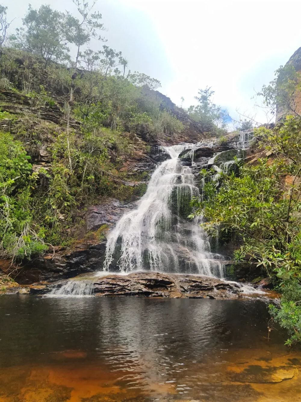 Cachoeira do Sossego falling over dark rock into a wide natural pool in Chapada Diamantina, Brazil.