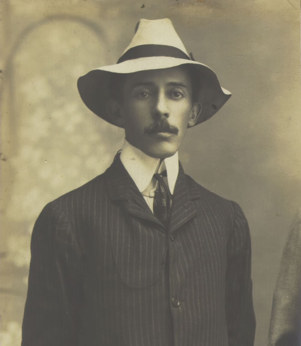 Sepia studio portrait of Brazilian aviation pioneer Santos Dumont wearing a white hat and a pinstripe suit