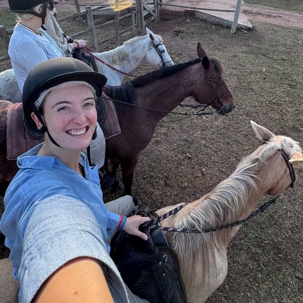 Sally takes a selfie on horseback next to a pale horse