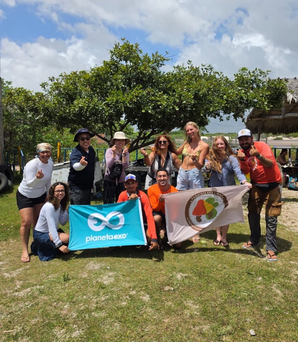 Trekking group posing with a PlanetaEXO flag in Lençóis Maranhenses