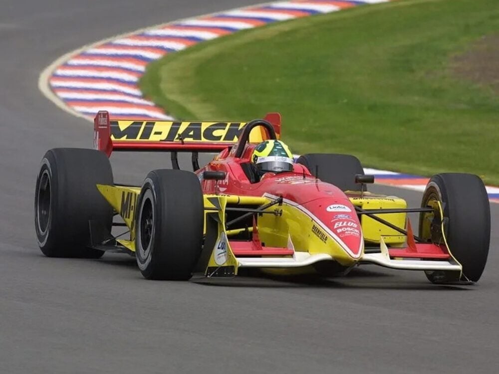 Mario Haberfeld’s red and yellow single-seater race car cornering on a circuit