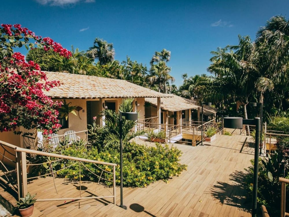 Sunny outdoor area of a rustic inn with a flowery garden, wooden ramps, and stairs connecting the room balconies. Sunny outdoor area of a rustic inn with a flowery garden, wooden ramps, and stairs connecting the room balconies.