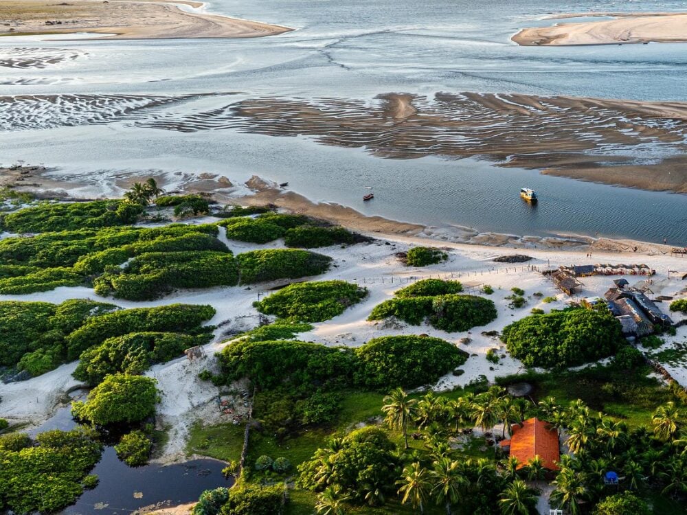 Lush aerial landscape of Atins, highlighting the green vegetation, sandbanks, and the meeting of the Preguiças River waters with the ocean. Lush aerial landscape of Atins, highlighting the green vegetation, sandbanks, and the meeting of the Preguiças River waters with the ocean.