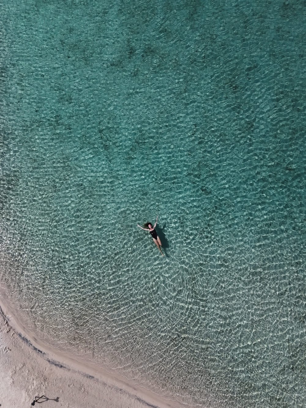 Top view of a woman floating in the calm, greenish waters of an exclusive lagoon during a trip to Lençóis Maranhenses. Top view of a woman floating in the calm, greenish waters of an exclusive lagoon during a trip to Lençóis Maranhenses.