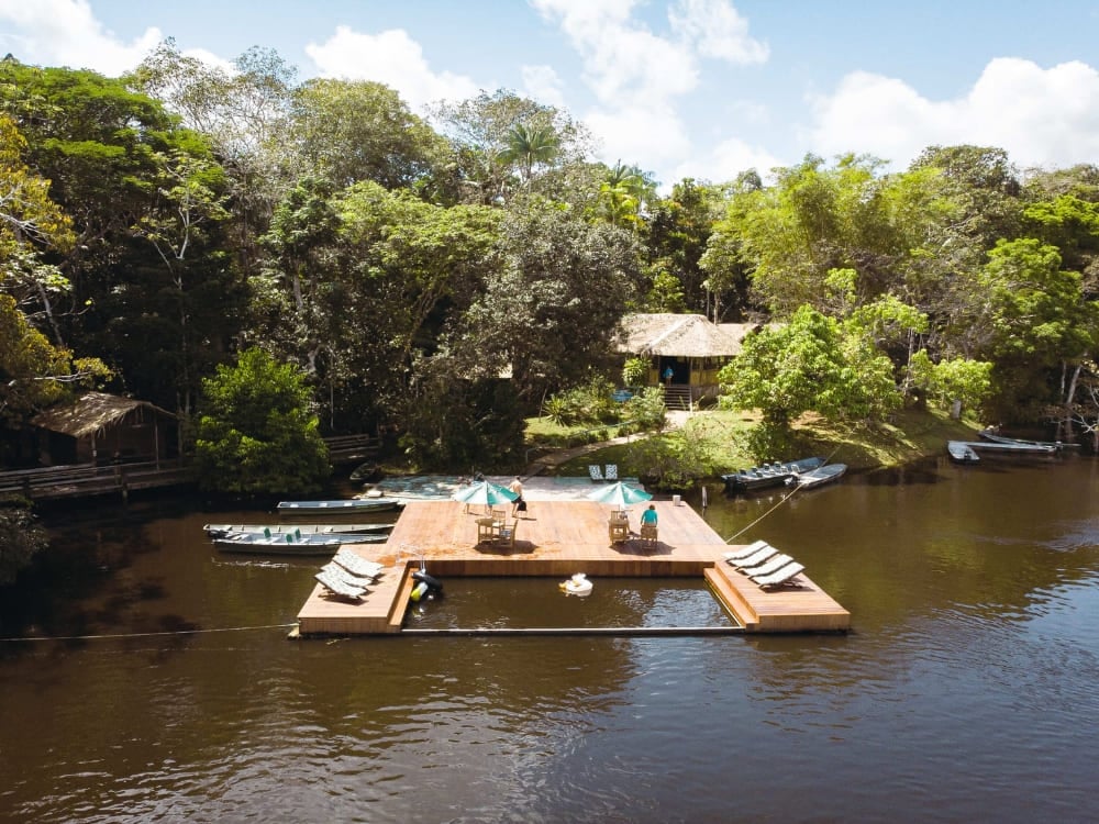 . Aerial view of Dolphin Lodge showing its floating deck, boats, and chalets surrounded by the Amazon forest.