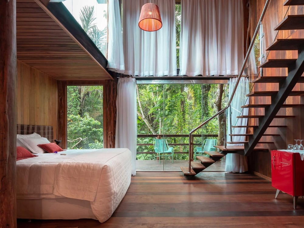 . A luxury room with a large glass window facing the forest at Mirante do Gavião in the Amazon rainforest.