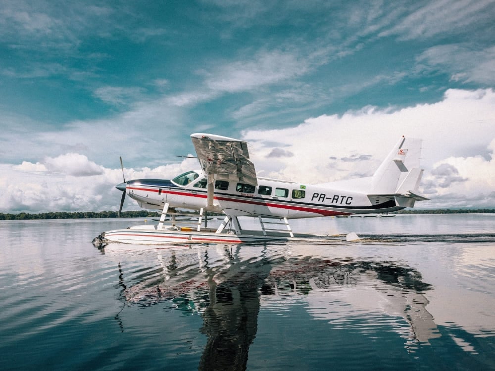 A white and red hydroplane floats on the calm Rio Negro, offering a transport option to the Amazon. A white and red hydroplane floats on the calm Rio Negro, offering a transport option to the Amazon.