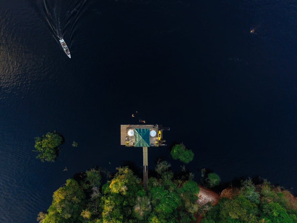 Aerial drone shot of an eco-lodge built on stilts surrounded by the dark waters of the Amazon river and lush jungle. Aerial drone shot of an eco-lodge built on stilts surrounded by the dark waters of the Amazon river and lush jungle.