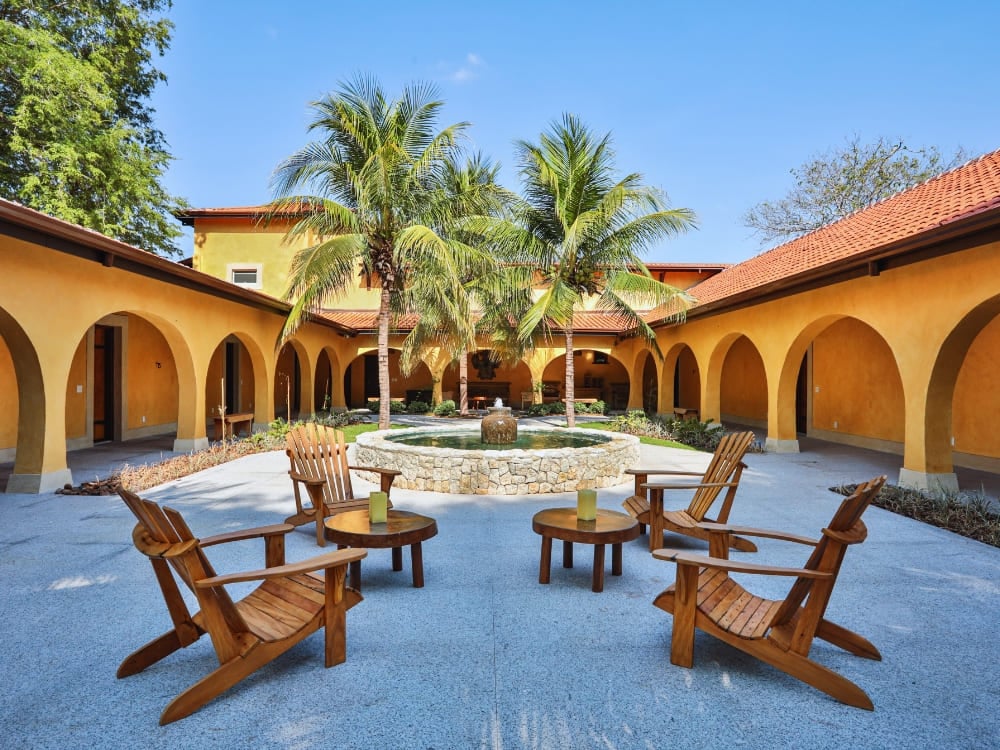 An elegant courtyard of one of the many Pantanal lodges, featuring yellow arches and wooden chairs around a fountain. An elegant courtyard of one of the many Pantanal lodges, featuring yellow arches and wooden chairs around a fountain.