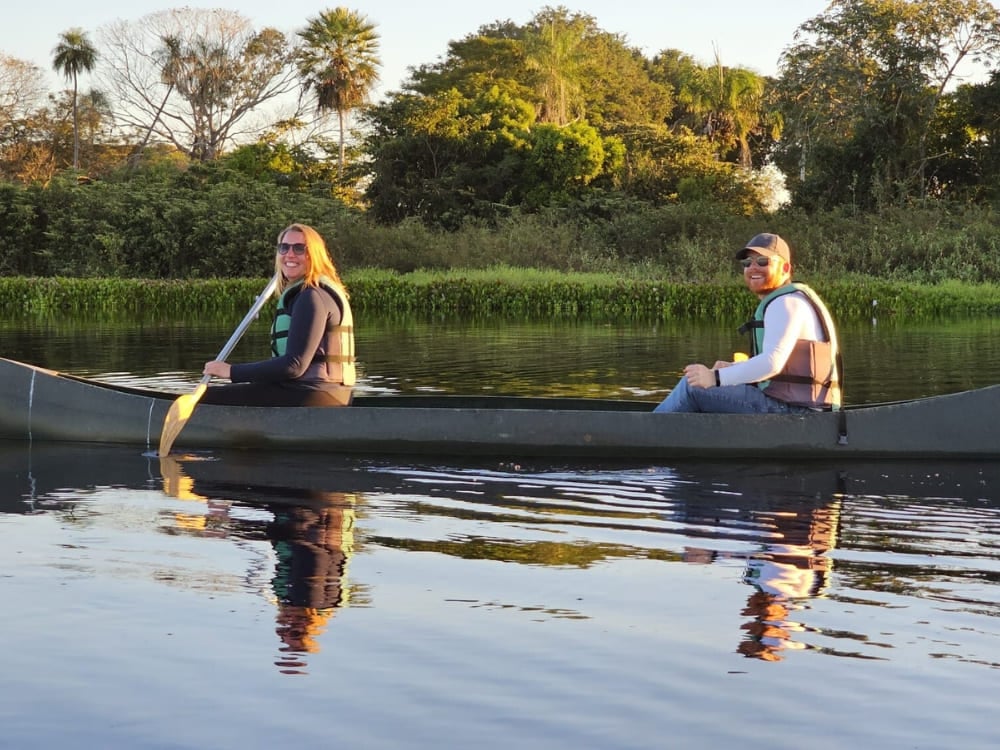 . Two travelers paddling a canoe through calm waters, an immersive way to explore the wetlands during a Pantanal tour.