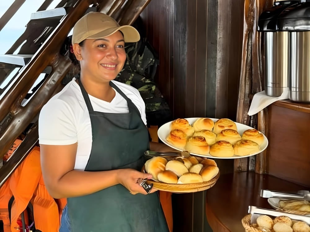 Woman in an apron holding plates with fresh bread on a vessel, representing the female financial independence achieved through tourism. Woman in an apron holding plates with fresh bread on a vessel, representing the female financial independence achieved through tourism.