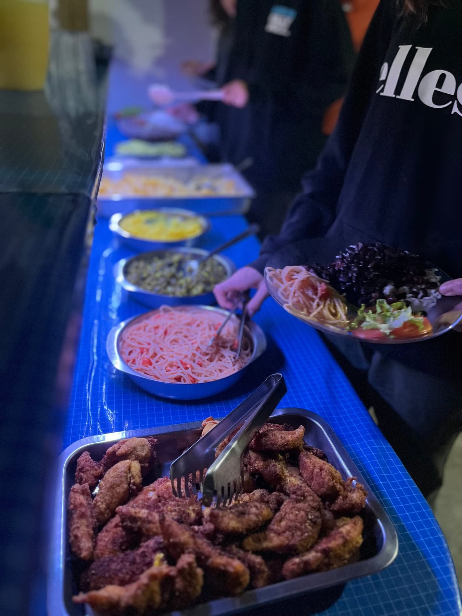 Home cooking that earns its place after a full day on the trail. A long buffet table set with multiple dishes including breaded fried meat, pasta with tomato sauce, lentils, and fresh salad, served at a local homestay on the Chapada Diamantina trek