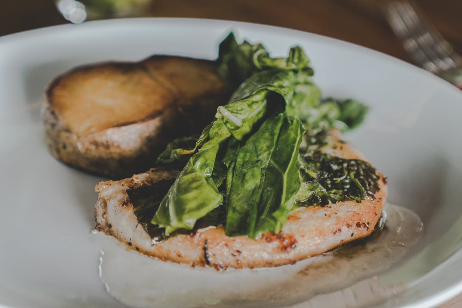 Simple ingredients, handled well. Lodge cooking that doesn't need to shout. Pan-seared fish fillet topped with fresh green leaves served alongside a roasted portobello mushroom on a white plate at Mirante do Gavião