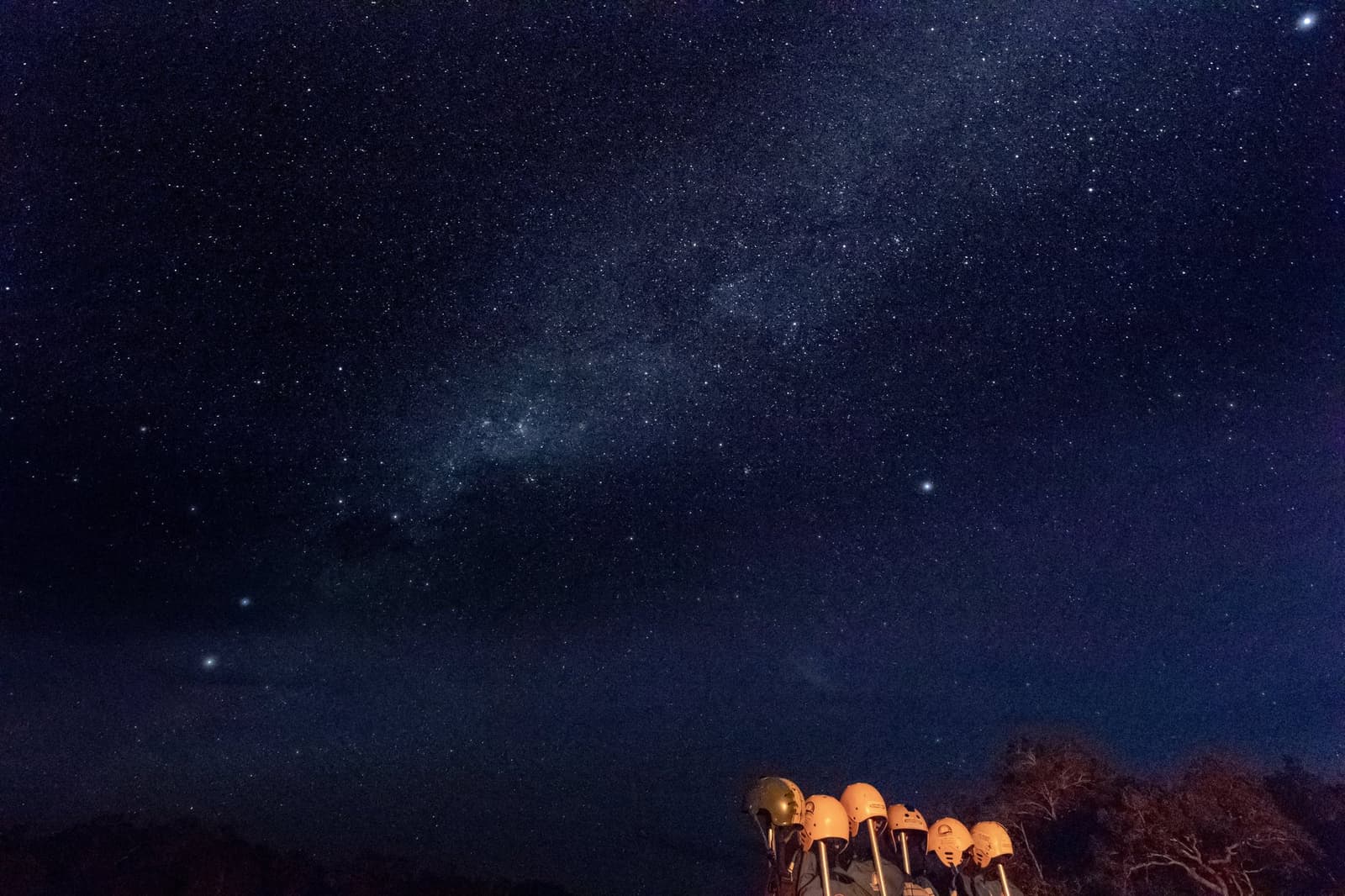 Telescopes ready, the cerrado dark enough to count the stars by hand. Photo: Alberto Andrich A row of telescopes glowing amber in the foreground beneath a vast Milky Way-filled night sky on a Jalapão trekking expedition