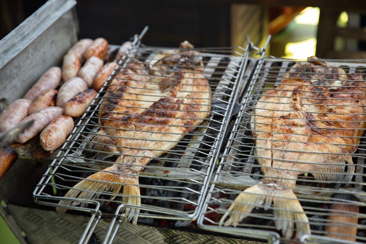 Fresh catch meets the grill, no ceremony required. Whole fish and sausages grilling on wire racks over charcoal at Mirante do Gavião, the traditional open-fire lunch served during the Anavilhanas excursion