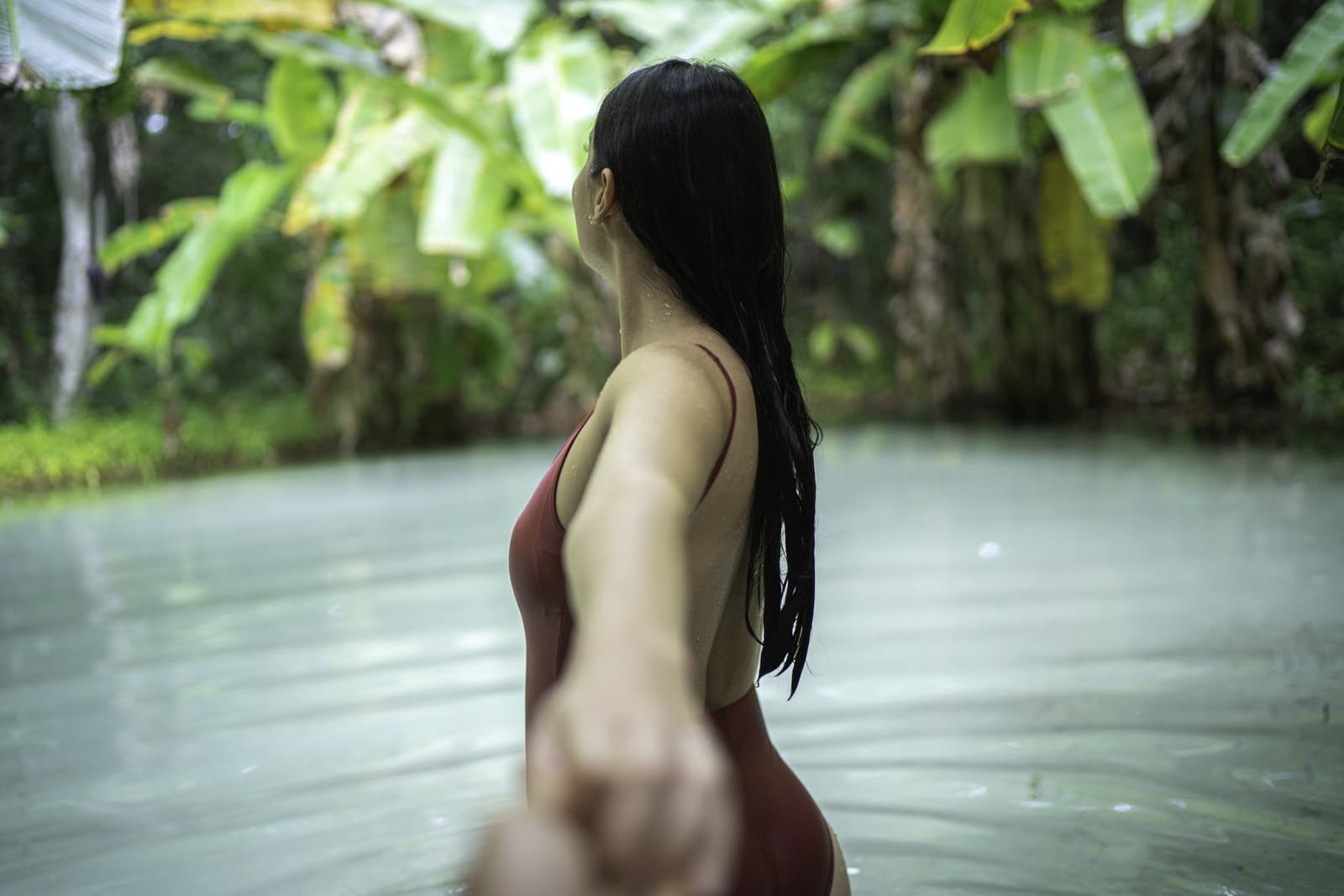 Cool water, no current — just you and the spring. Photo: FG Trade A woman in a red swimsuit wading through the calm, milky-green waters of a fervedouro on a 4-day Jalapão tour, surrounded by lush tropical vegetation