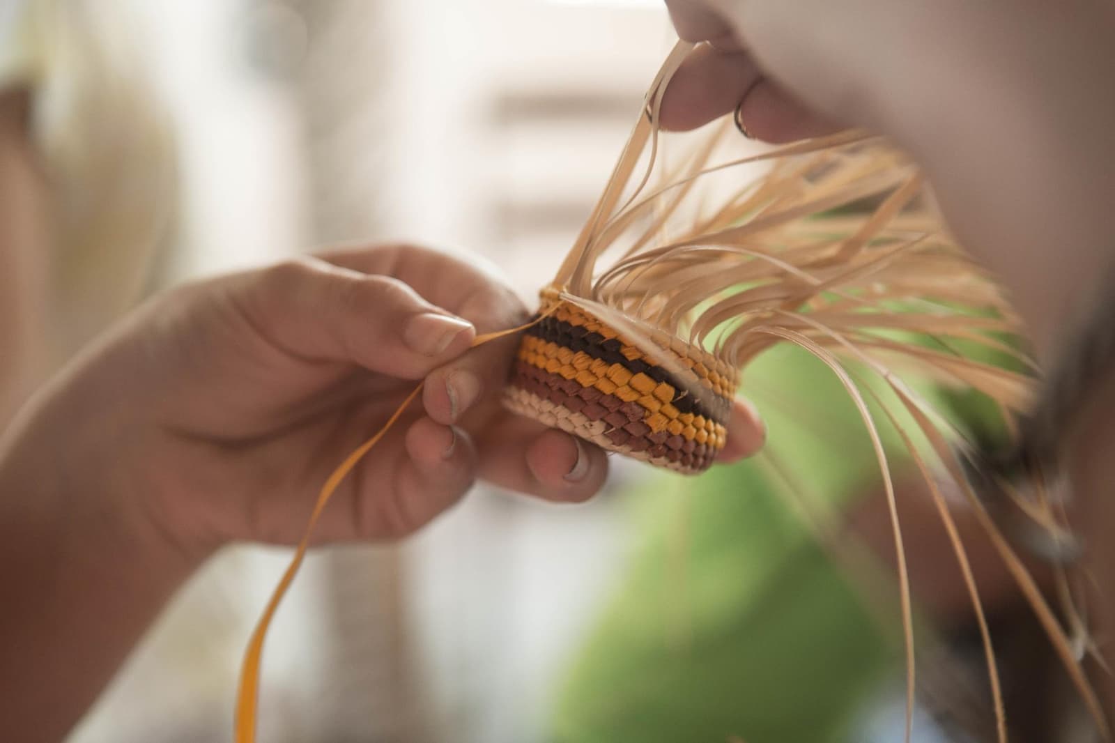 Every stripe is a choice, and every coil takes patience most of us forgot we had. Close-up of hands weaving a small striped basket with natural palm fibre strands during an Amazon cruise from Alter do Chão community visit