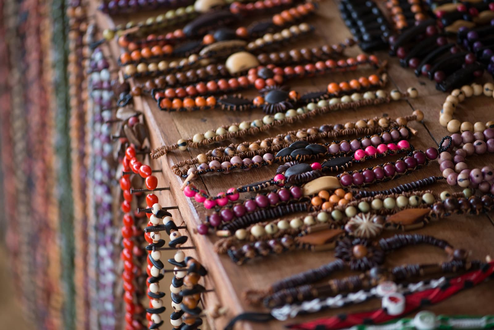 Every bead has a story the forest started. Rows of handmade bracelets strung with colourful natural seeds and wooden beads displayed on a wooden board at a riverside community near Anavilhanas Jungle Lodge Brazil