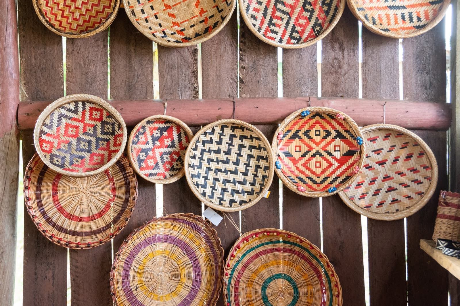 Every pattern tells a story, no two baskets quite the same. A wall of colorful handwoven round baskets with geometric and concentric patterns displayed at a riverside community near Anavilhanas Jungle Lodge Brazil