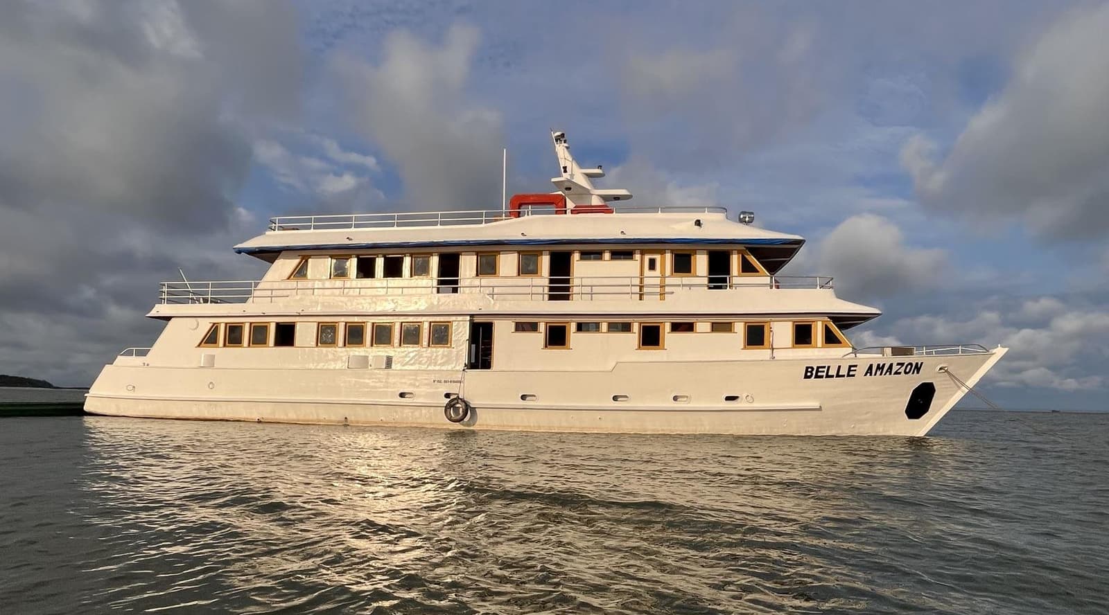 Your floating base for the next few days, not bad at all. The Belle Amazon multi-deck river cruise ship moored on calm water under a dramatic cloudy sky, part of the Amazon cruise from Alter do Chão experience