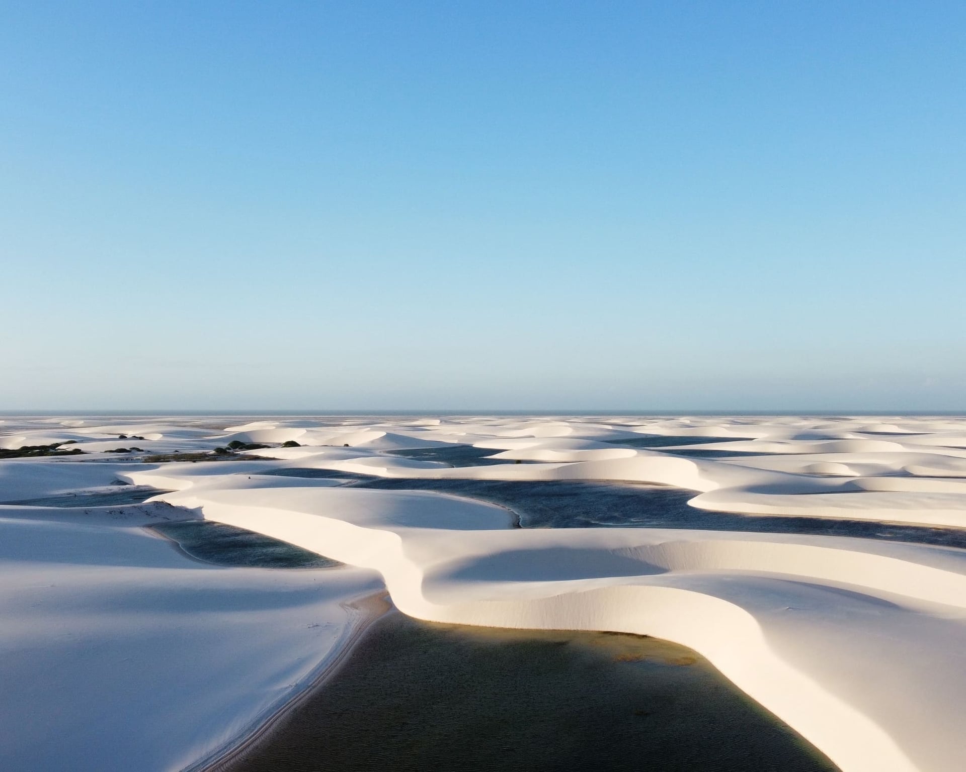 White sand dunes and turquoise rainwater pools across Lençóis Maranhenses National Park White sand dunes and turquoise rainwater pools across Lençóis Maranhenses National Park
