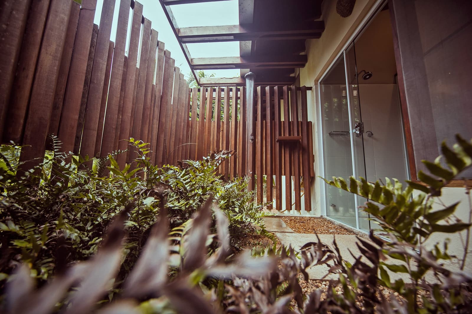 Your own slice of forest, right outside the bathroom door. A private outdoor shower enclosure at Cristalino Jungle Lodge, framed by vertical hardwood slats and lush tropical undergrowth beneath an open sky