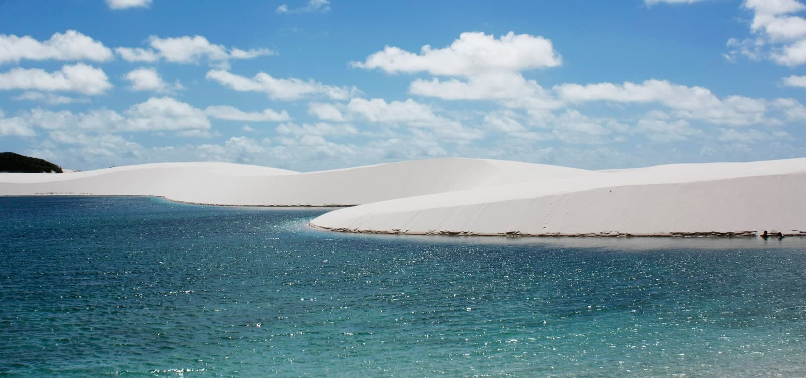 Sand and water in a combination that really shouldn't work this well. Crystal-clear blue lagoon reflecting a brilliant sky, framed by sweeping white sand dunes — the iconic landscape of the horseback riding Lençóis Maranhenses tour