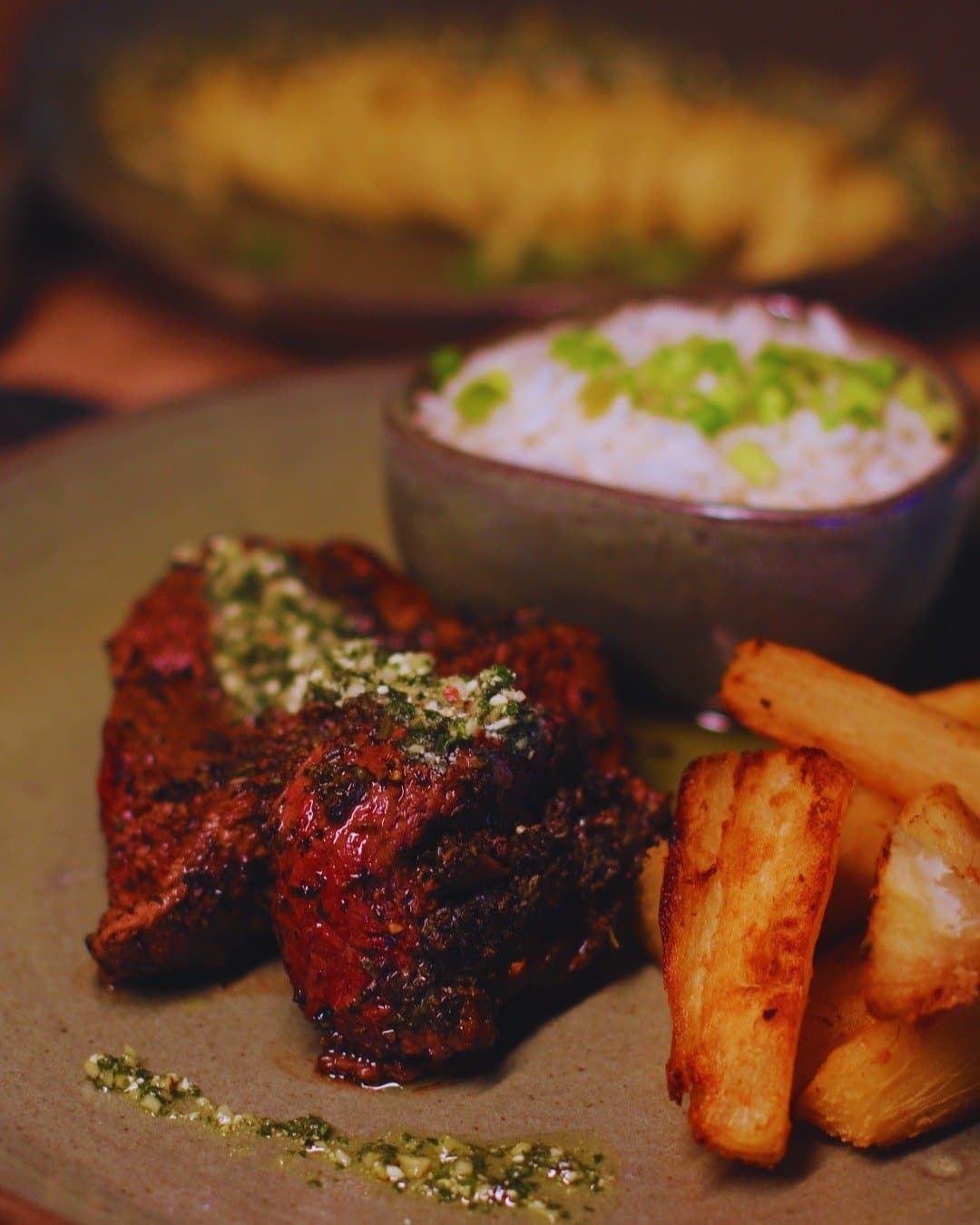 Lodge food in the Amazon hits differently after a morning on the river. A herb-crusted grilled meat fillet topped with chimichurri, served with fried cassava sticks and a bowl of white rice with spring onions at Juma Amazon Jungle Lodge