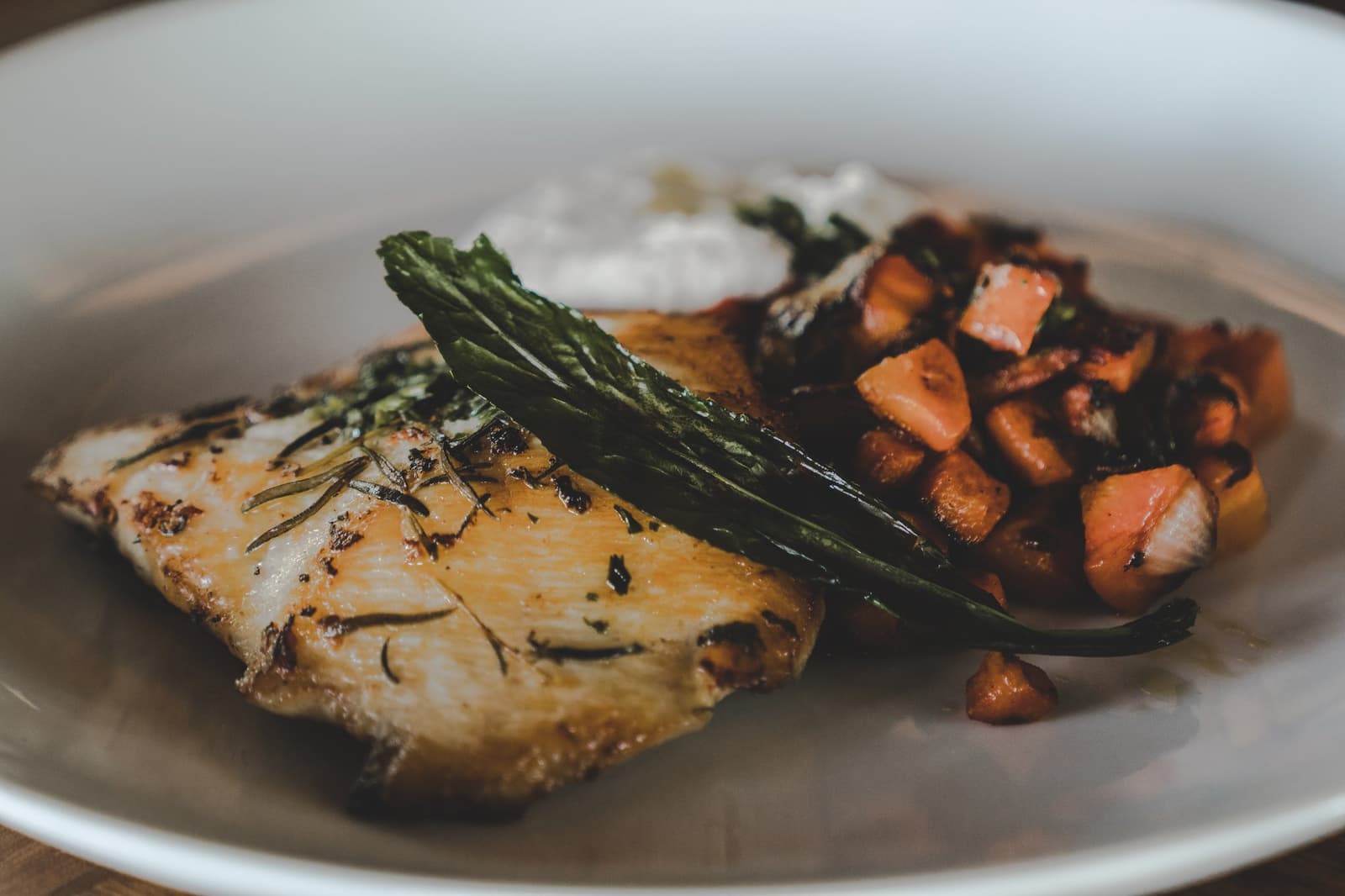 Lodge cooking that actually does the river justice. A golden herb-crusted fish fillet served at a luxury Amazon lodge Brazil restaurant, topped with wilted greens and accompanied by sautéed diced root vegetables and a cream sauce