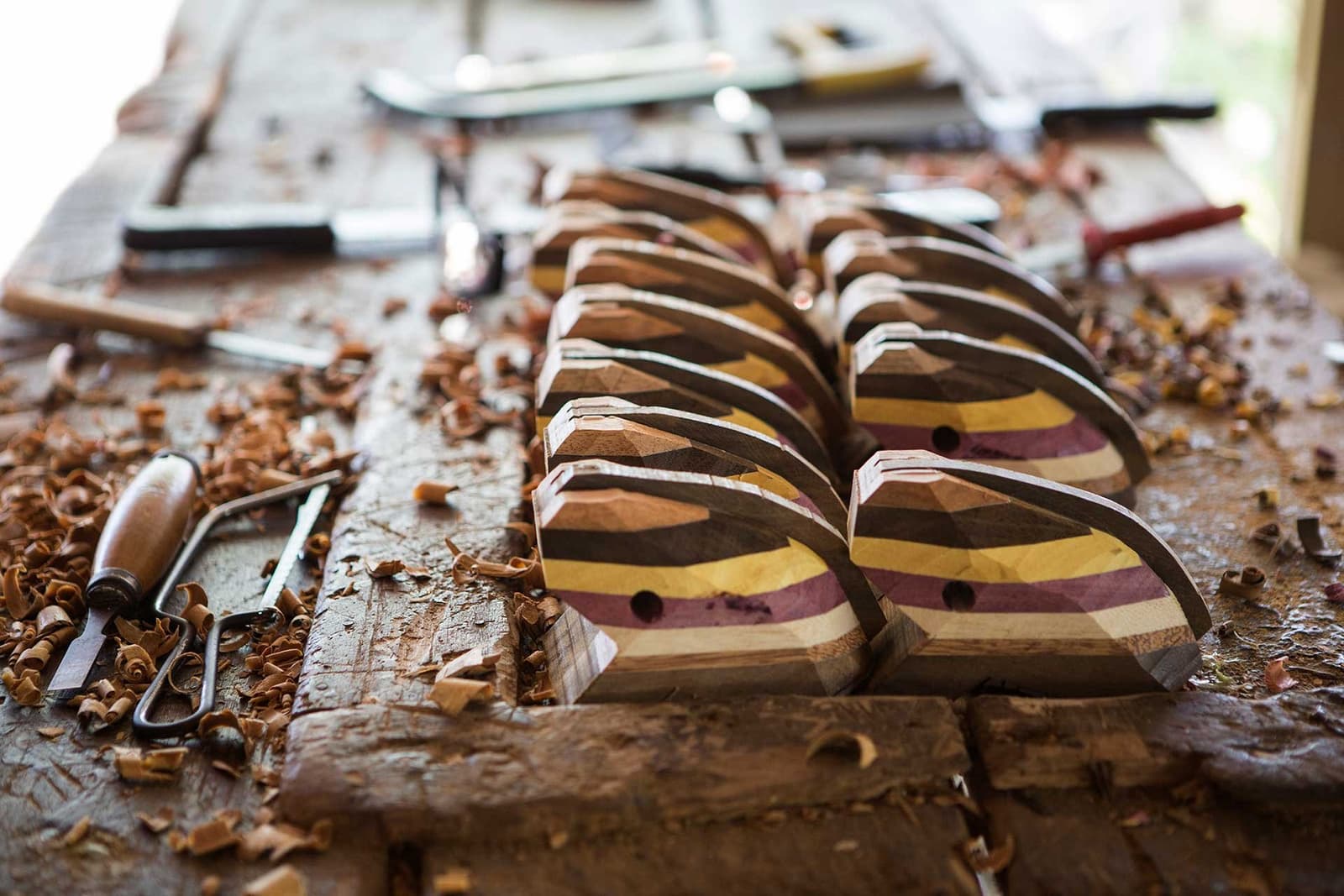 Local craft, made one shaving at a time. Rows of handcrafted multicoloured laminated wood pieces in progress on a workbench scattered with shavings and carving tools, reflecting the artisan handicraft culture near this luxury amazon lodge brazil