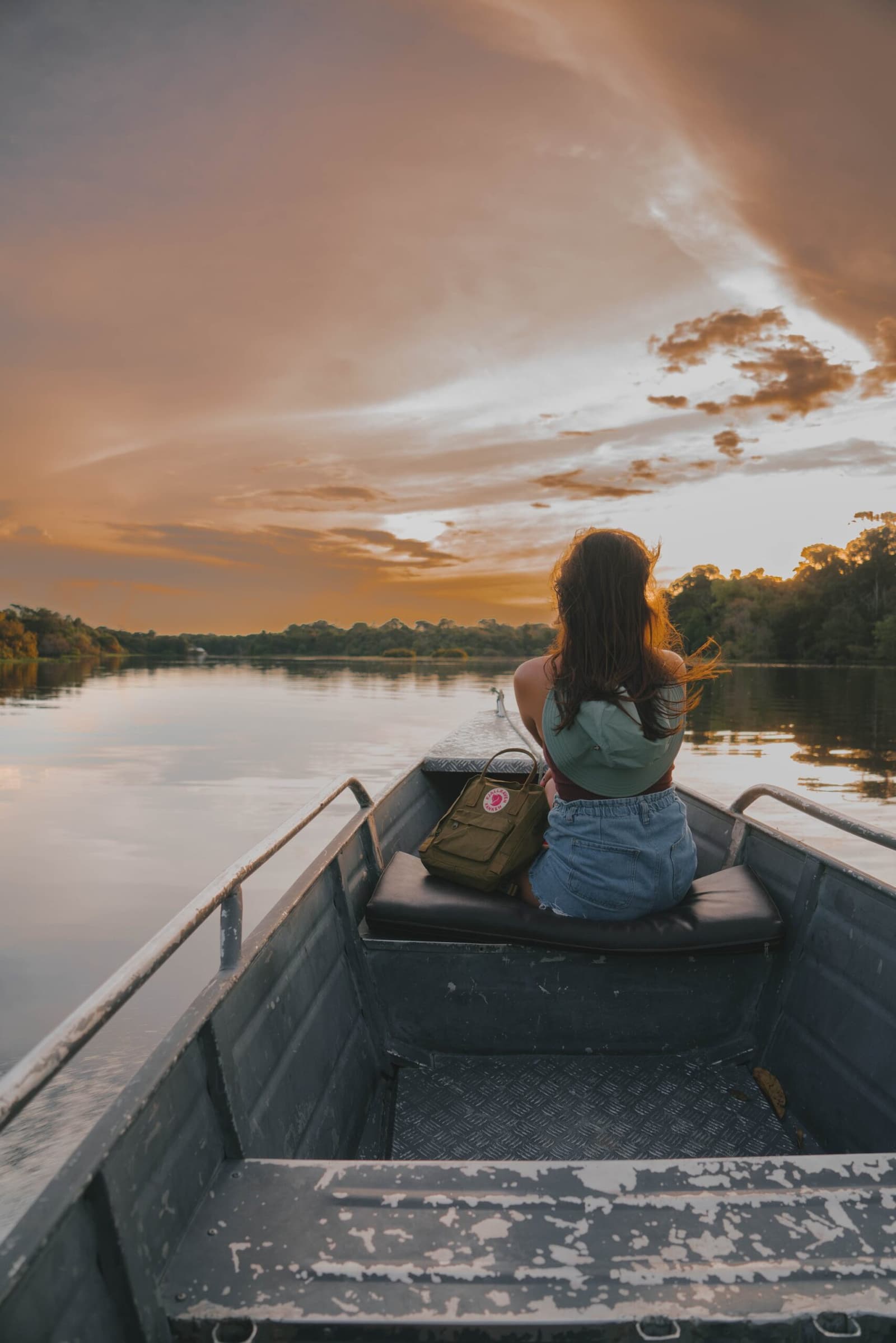 Golden hour on the river — hair catching the breeze, nothing ahead but open water and burning sky. Photo: Yuri Panichi Photo 1