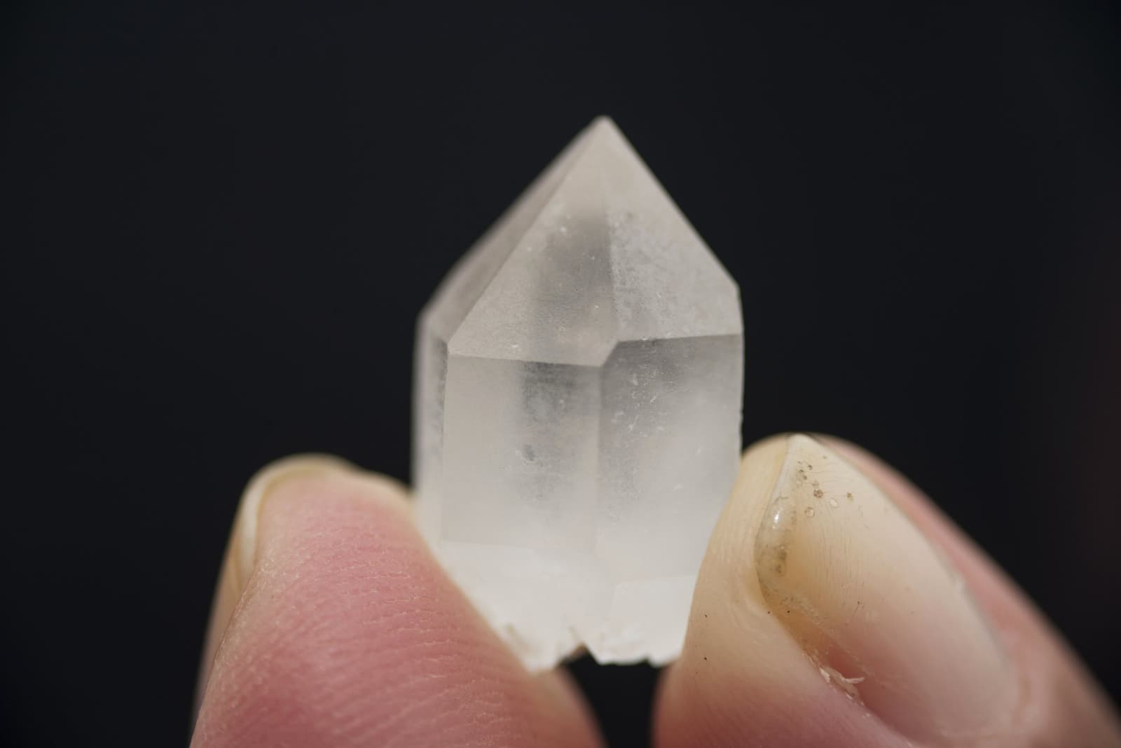 Roraima gives you souvenirs you can't put in your bag. A small clear quartz crystal point held between two fingers against a black background, found in the Valley of Crystals on the Mount Roraima hike