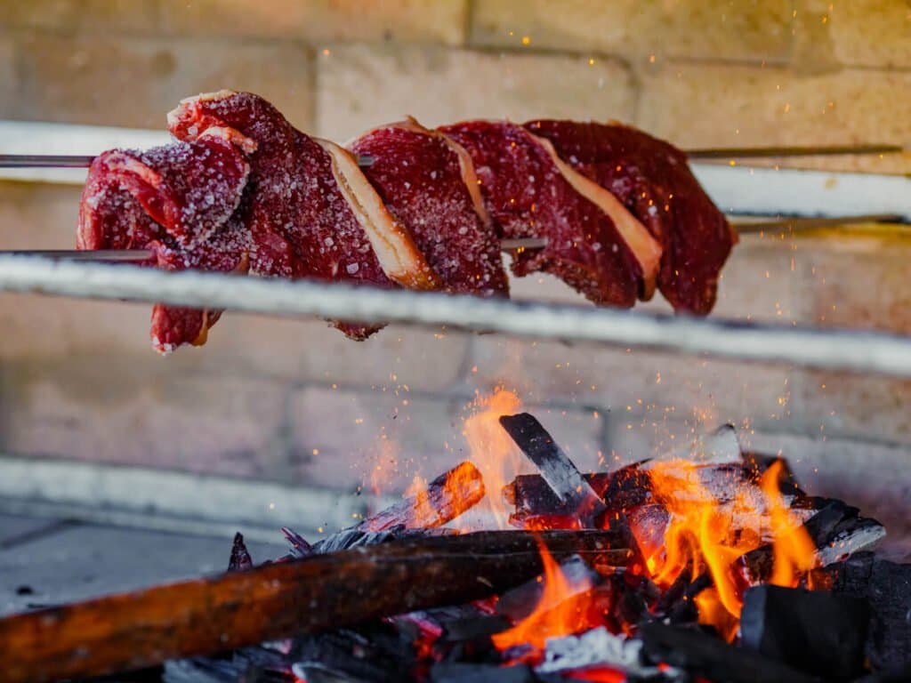 Salt, fire, patience. Some things the Pantanal gets exactly right. Salt-crusted beef on metal skewers cooking over open wood flames at a lodge during a pantanal jaguar safari porto jofre trip