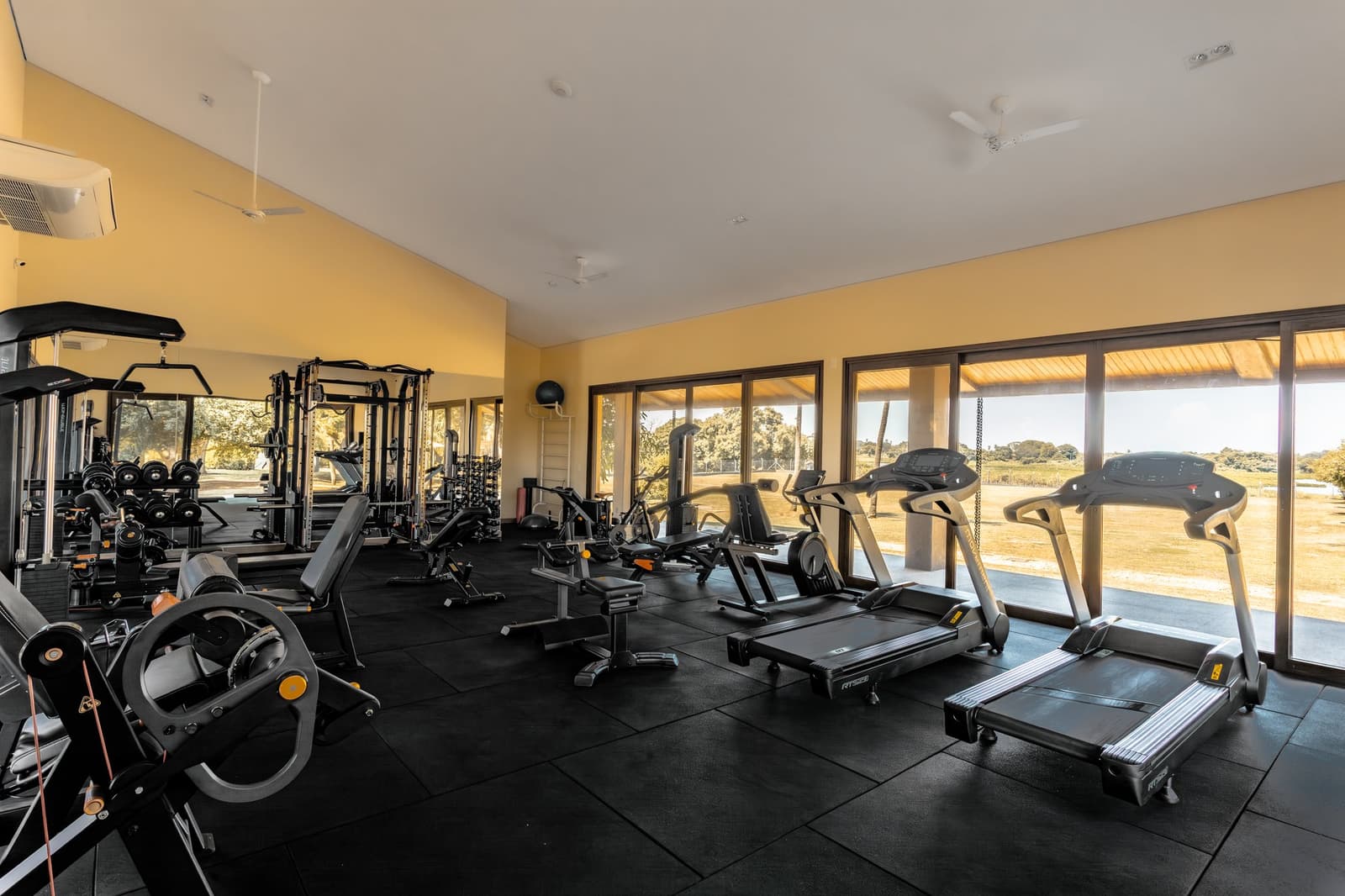 Keep your routine, the view from the treadmill does the motivating. Fully equipped fitness center at a pantanal luxury safari lodge, with treadmills, weight machines, and floor-to-ceiling windows overlooking an open savanna landscape