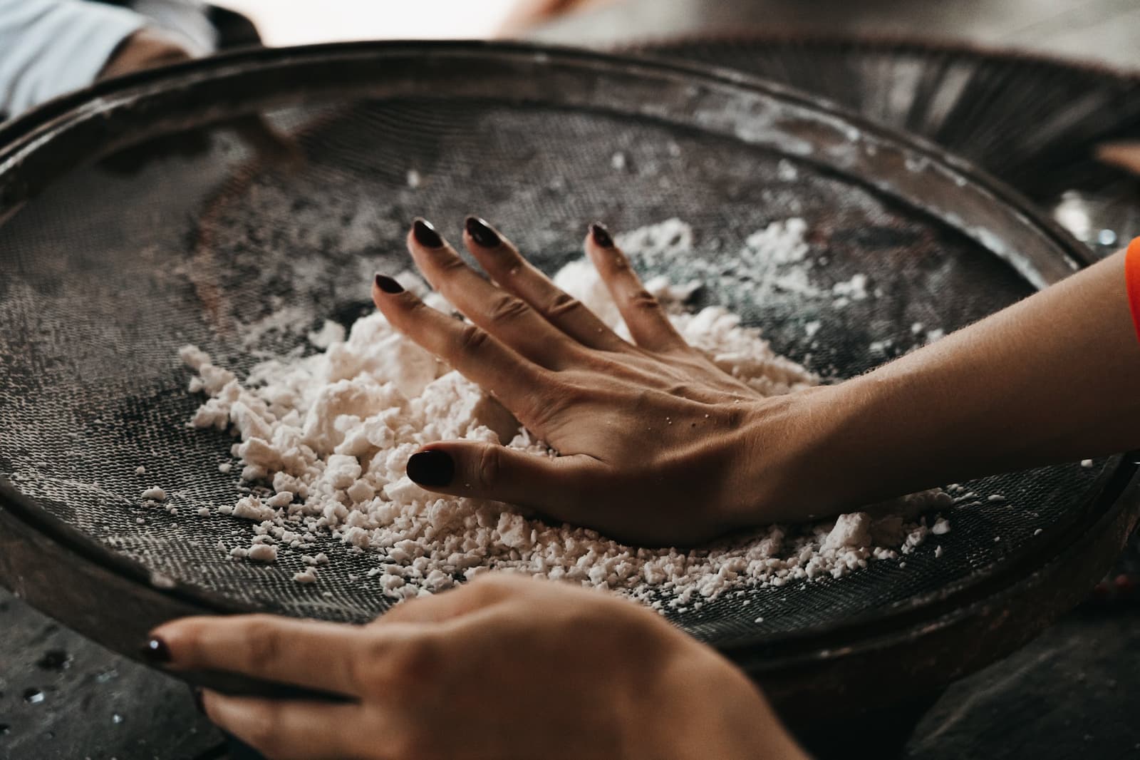 Cassava flour doesn't start in a bag, it starts like this. Hands pressing grated cassava through a large wire sieve during a community visit on the untamed amazon cruise