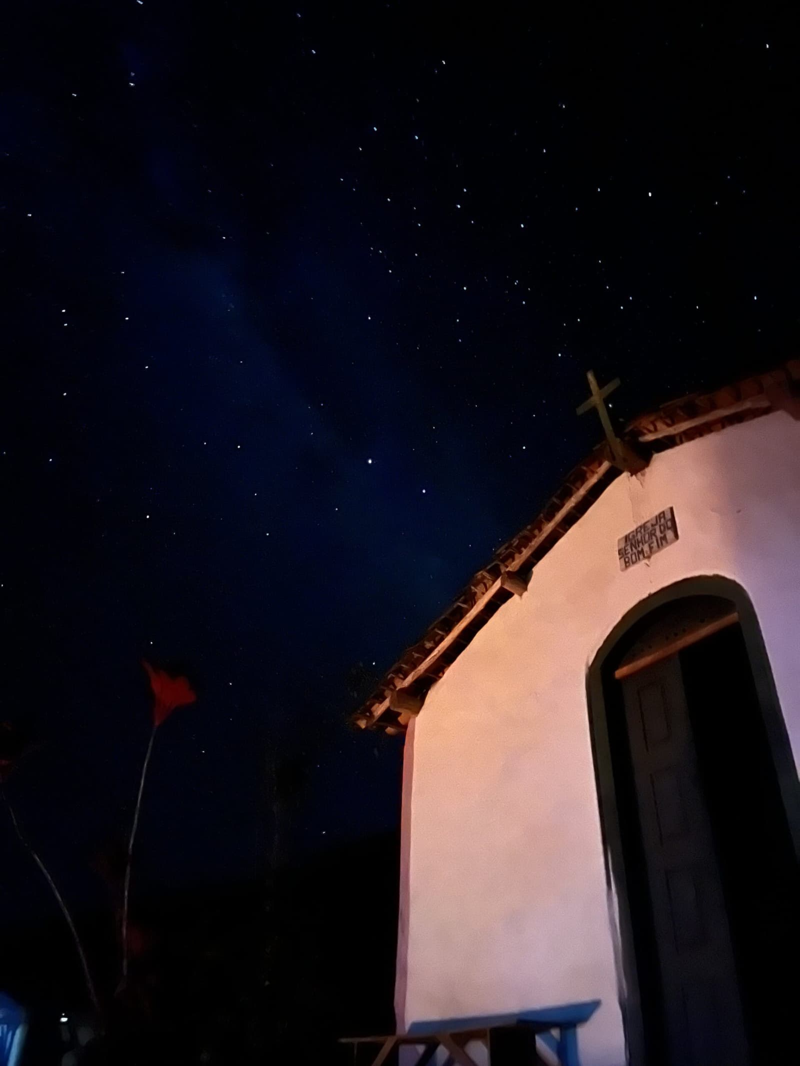 Old walls, older stars. Some nights in the Chapada just stop you cold. A whitewashed colonial chapel signed 'Igreja Senhor do Bonfim' beneath a brilliant starry sky on the Vale do Pati Trek, with a wooden cross silhouetted against the deep blue night