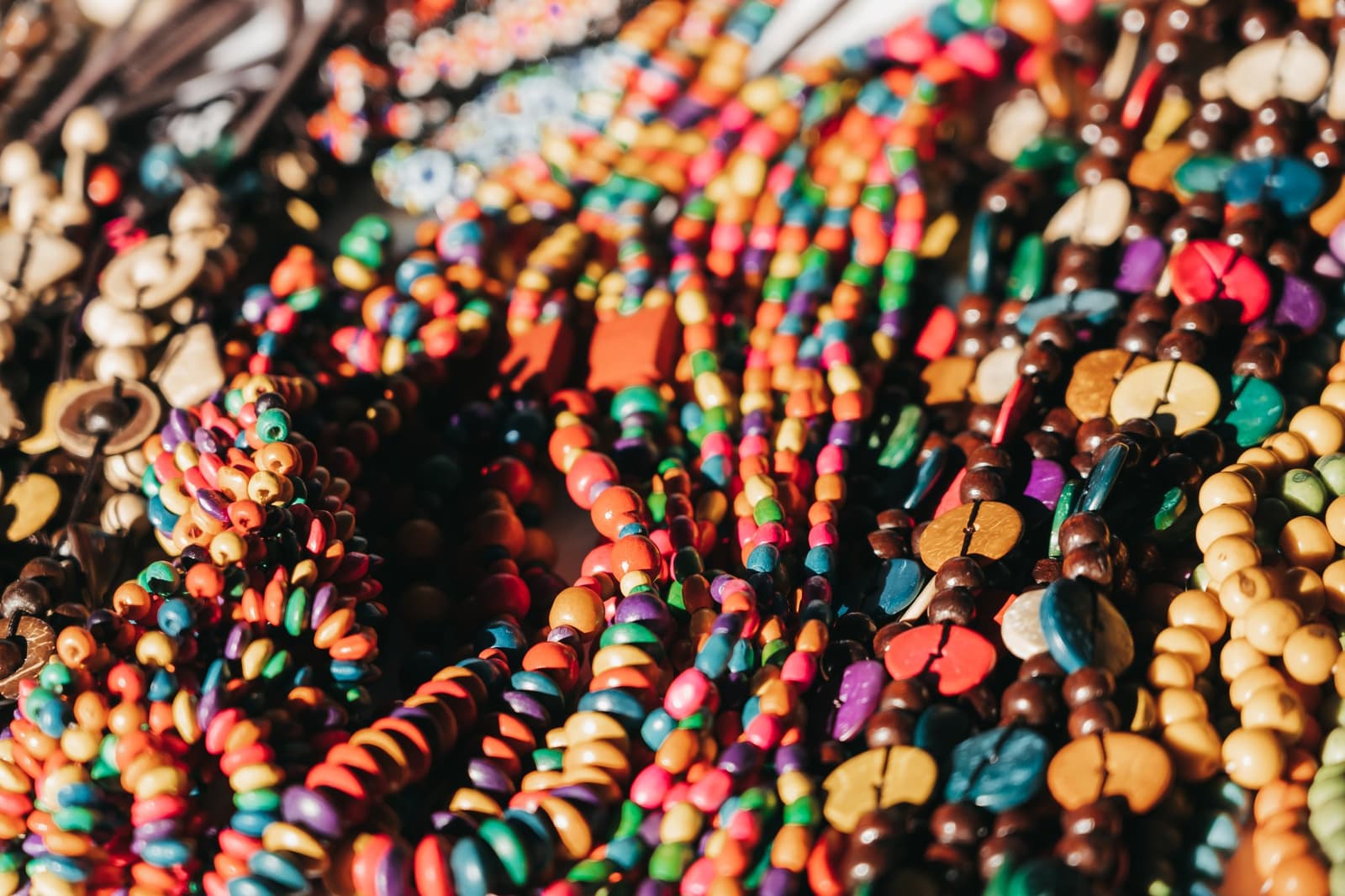 Hard to pick just one, and that is entirely the point. A close-up of dozens of colorful handmade beaded necklaces with wooden and seed beads in red, orange, blue, green, purple, and brown, displayed at a local market during a luxury Amazon cruise in Brazil.