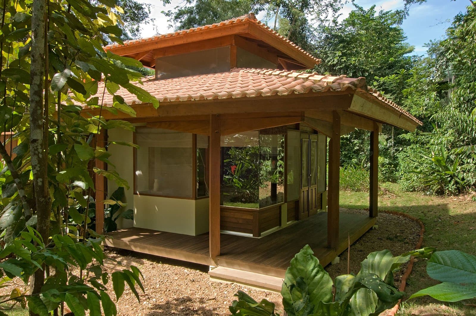 Small footprint, big forest all around, this is the right kind of room. Photo: Luis Gomes A compact wooden chalet with a terracotta-tiled hip roof, large glass panels, and a hardwood deck, set among lush tropical garden greenery on this luxury Pantanal and Amazon trip
