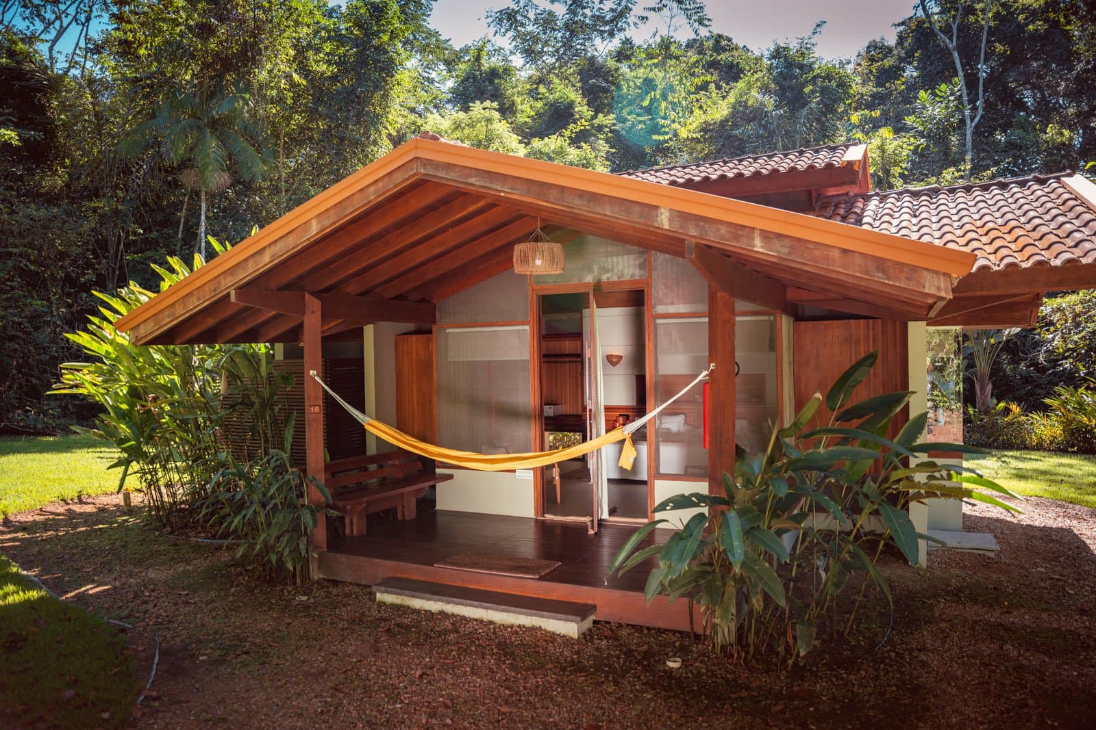 A yellow hammock, a wooden deck, and the forest right there waiting. Photo: Samuel Melim A timber-framed eco-lodge bungalow on a luxury Pantanal and Amazon trip, with a yellow hammock strung across the covered veranda and dense tropical forest rising behind it