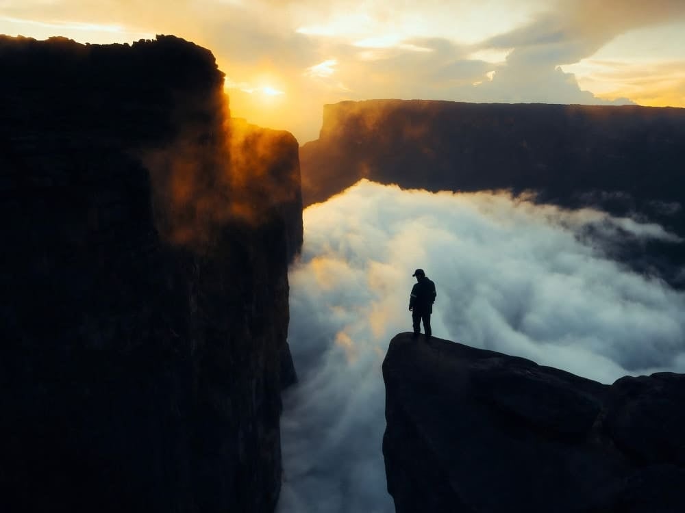 Sunset over the cliff edge of Mount Roraima's summit, above a sea of clouds Sunset over the cliff edge of Mount Roraima's summit, above a sea of clouds