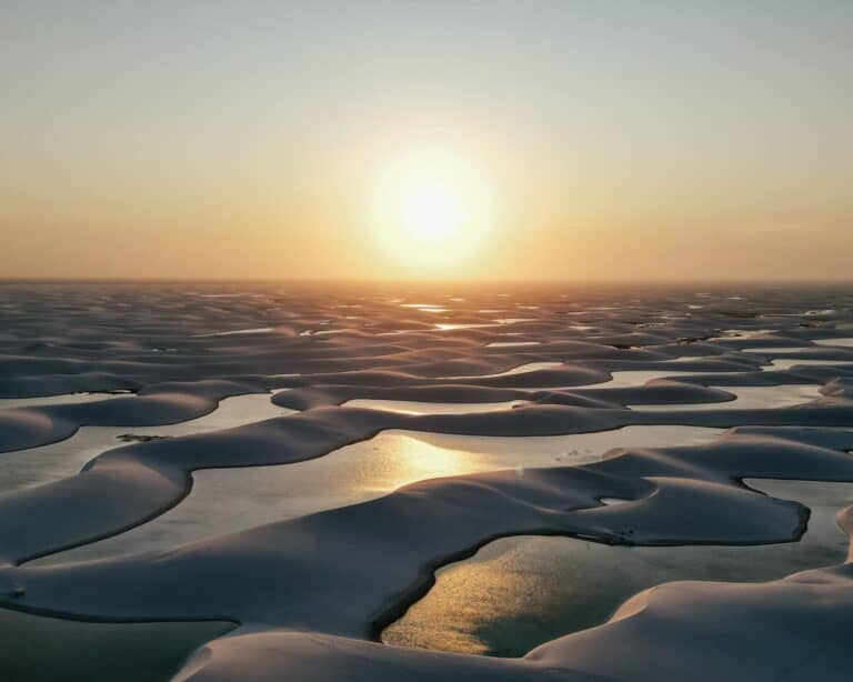 Aerial view of the white sand dunes and rainwater lagoons of Lençóis Maranhenses at sunset, Brazil.