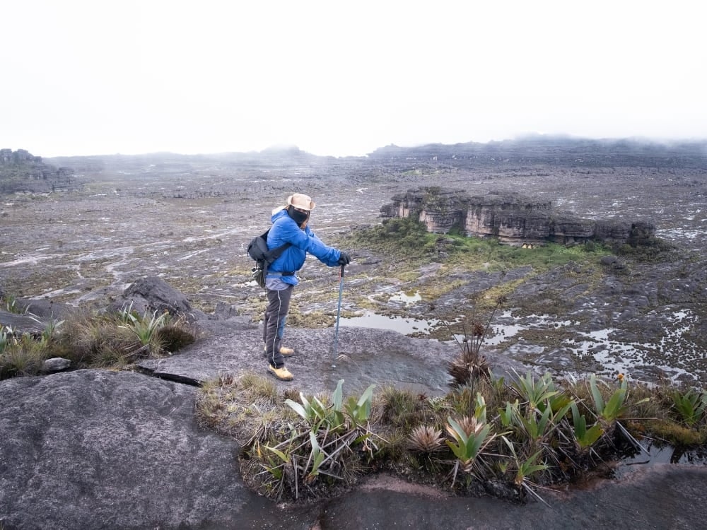 Hiker on Mount Roraima's rocky summit plateau in the mist during the Roraima trek Hiker on Mount Roraima's rocky summit plateau in the mist during the Roraima trek