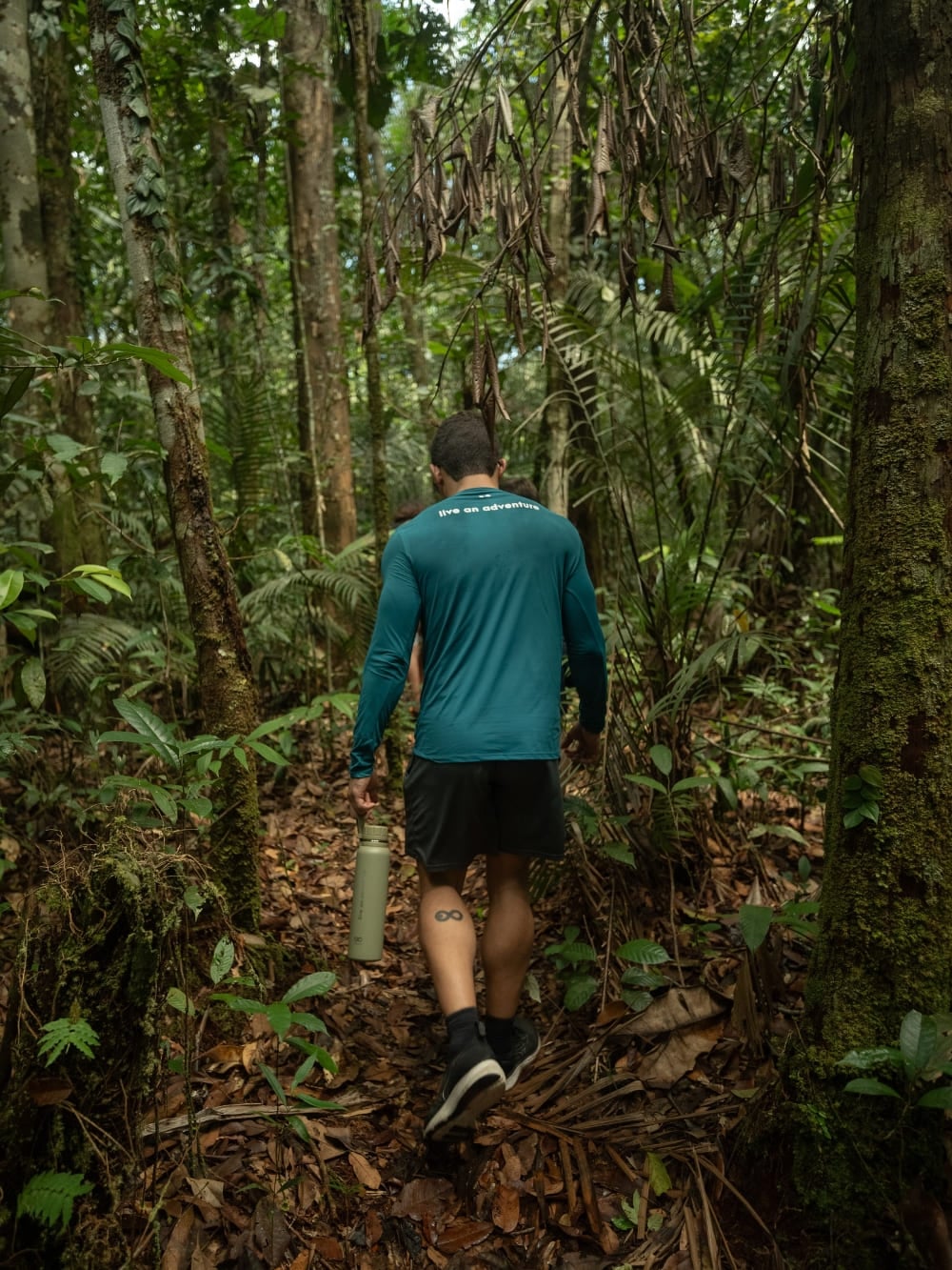 Photo: Marcelo Bonifácio Traveler carrying a water bottle on a jungle trail in the Amazon Rainforest in Brazil