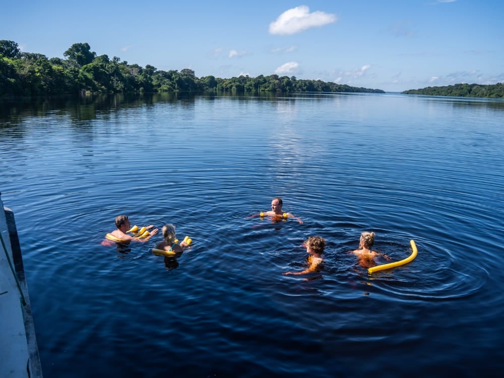Photo: Felipe Castellari Travelers swimming with floats beside the boat in the Amazon River in Brazil
